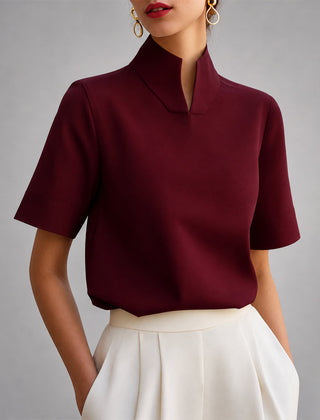 Women's red short-sleeve structured blouse with a V-cut mock neck.
