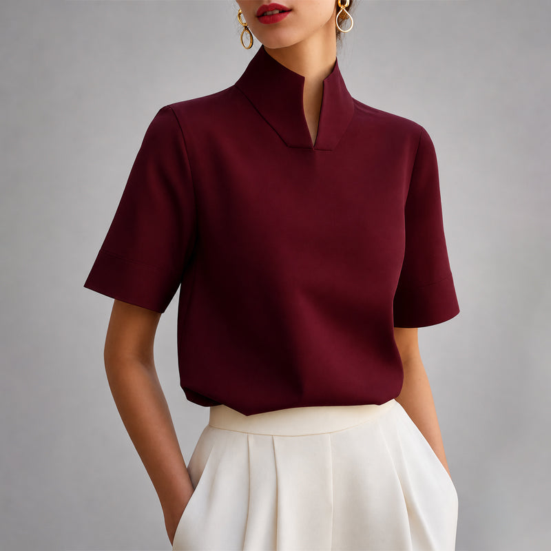 Women's red short-sleeve structured blouse with a V-cut mock neck.