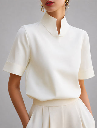 Women's white short-sleeve structured blouse with a V-cut mock neck.