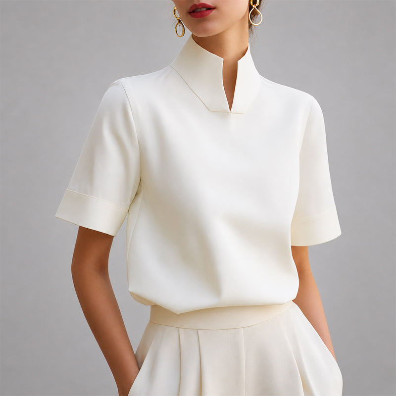 Women's white short-sleeve structured blouse with a V-cut mock neck.
